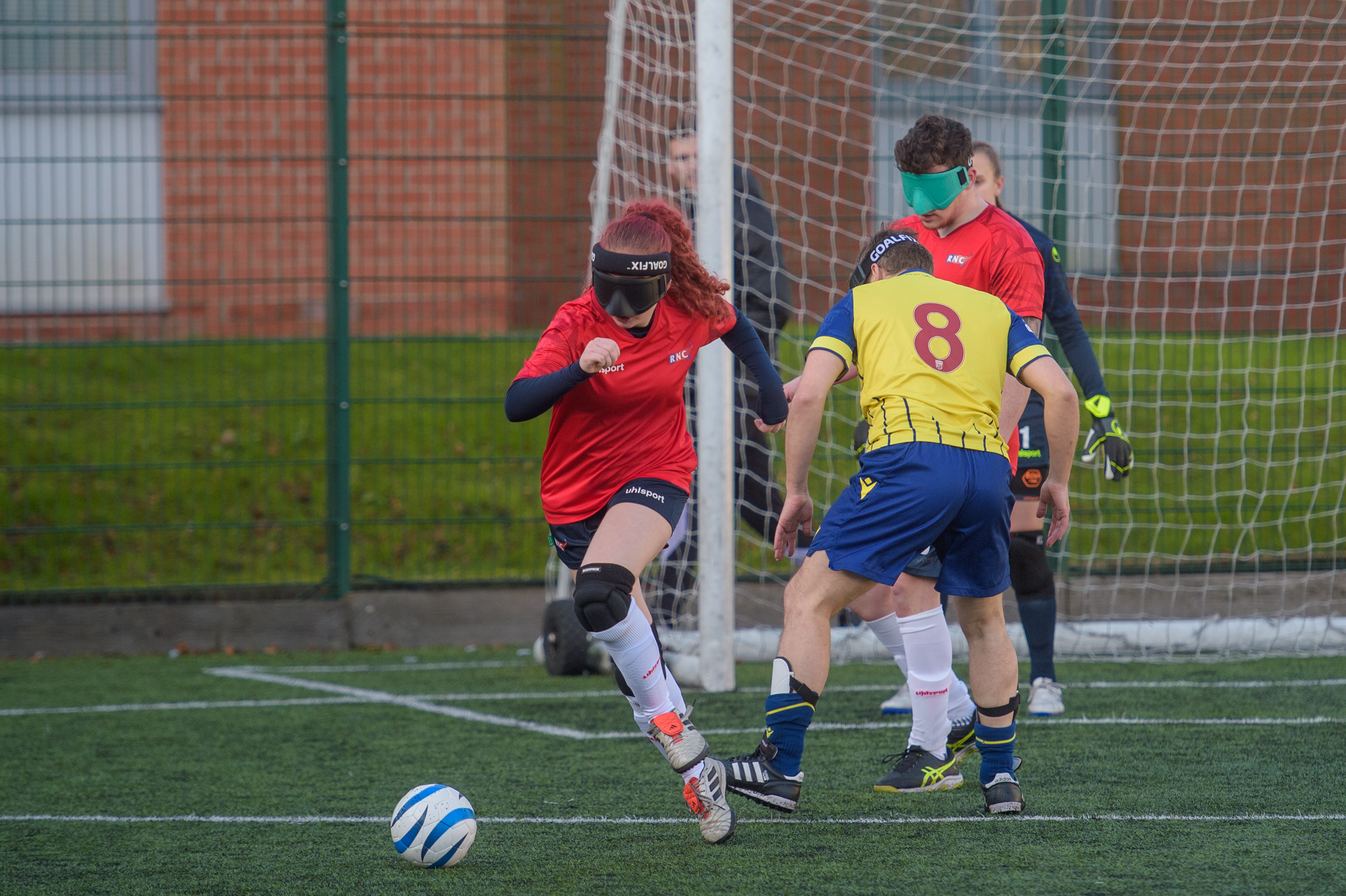 RNC player Amelie, running after the ball away from goal with an RNC and WBA player in the background along with the RNC goalie