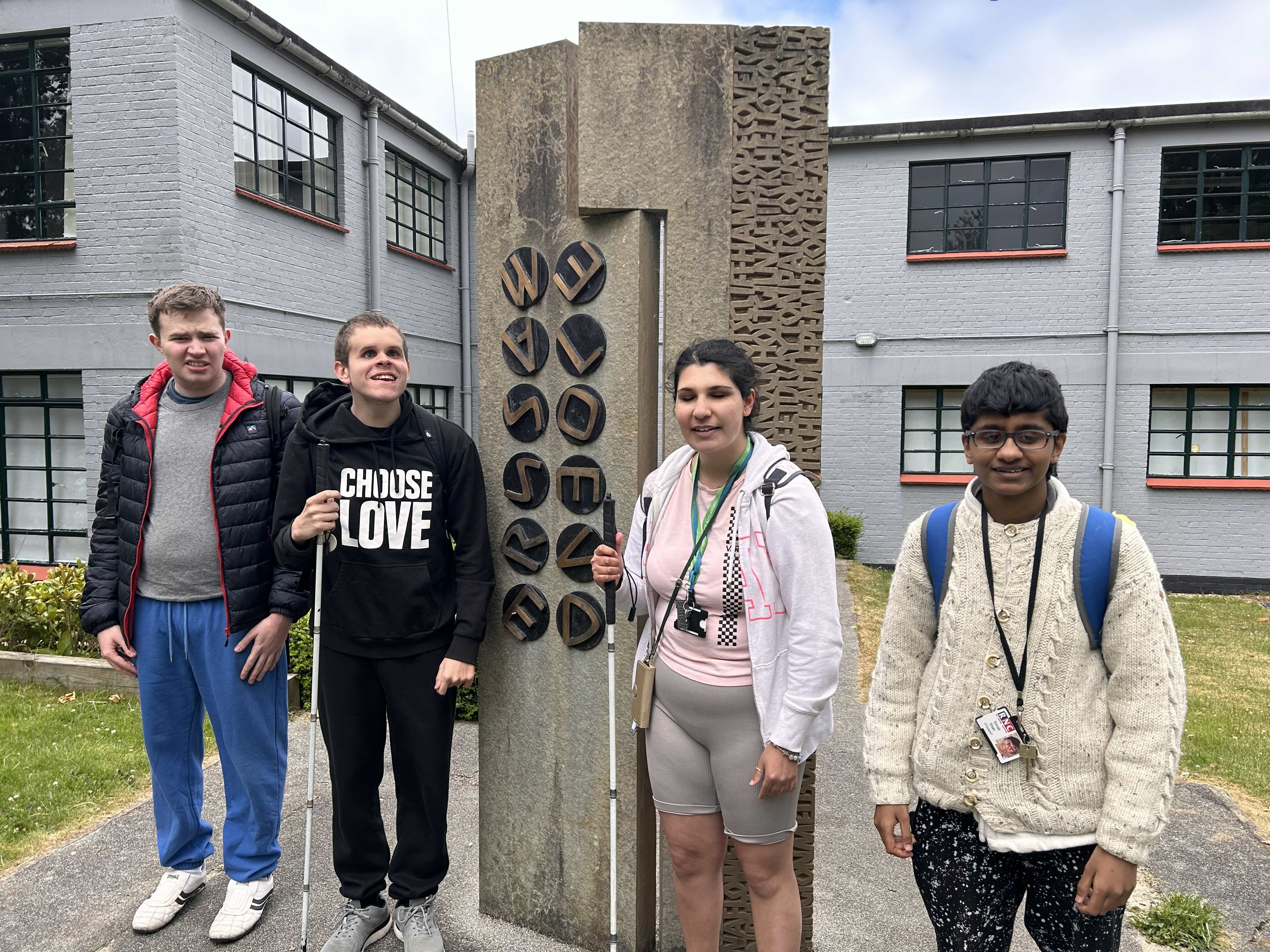 a group of four students standing next to the Bletchley Park memorial