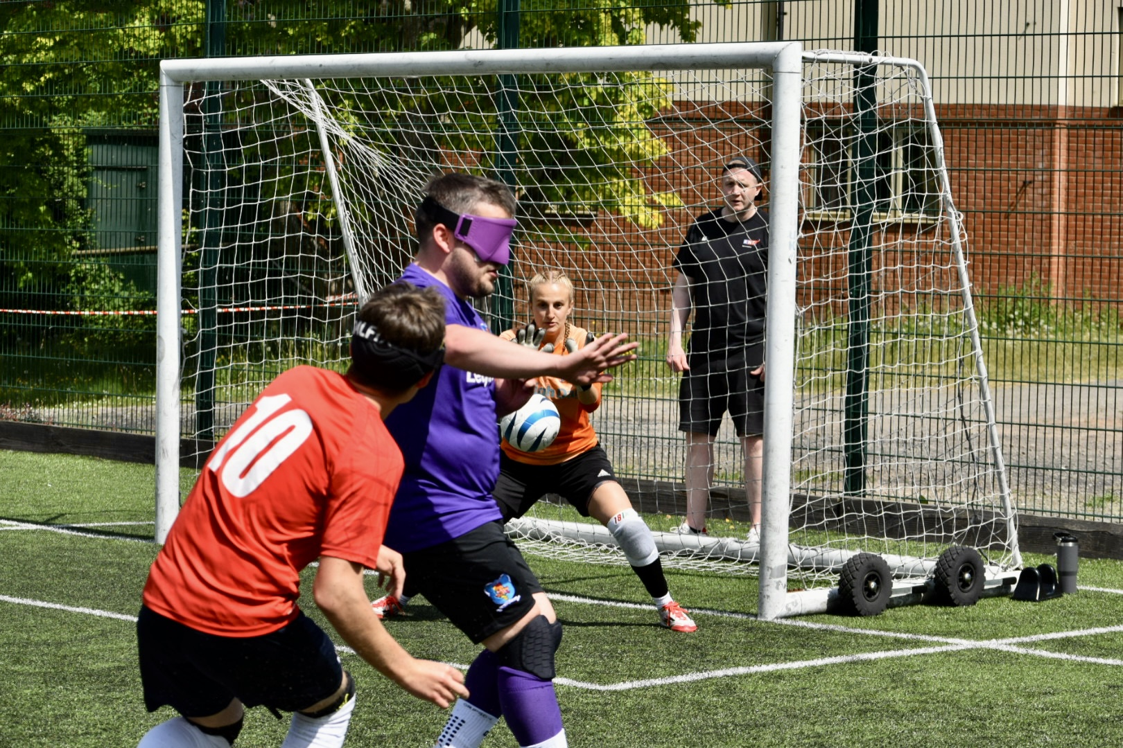 RNC player strikes the ball towards Merseyside goalie as a Merseyside player tries to block the ball