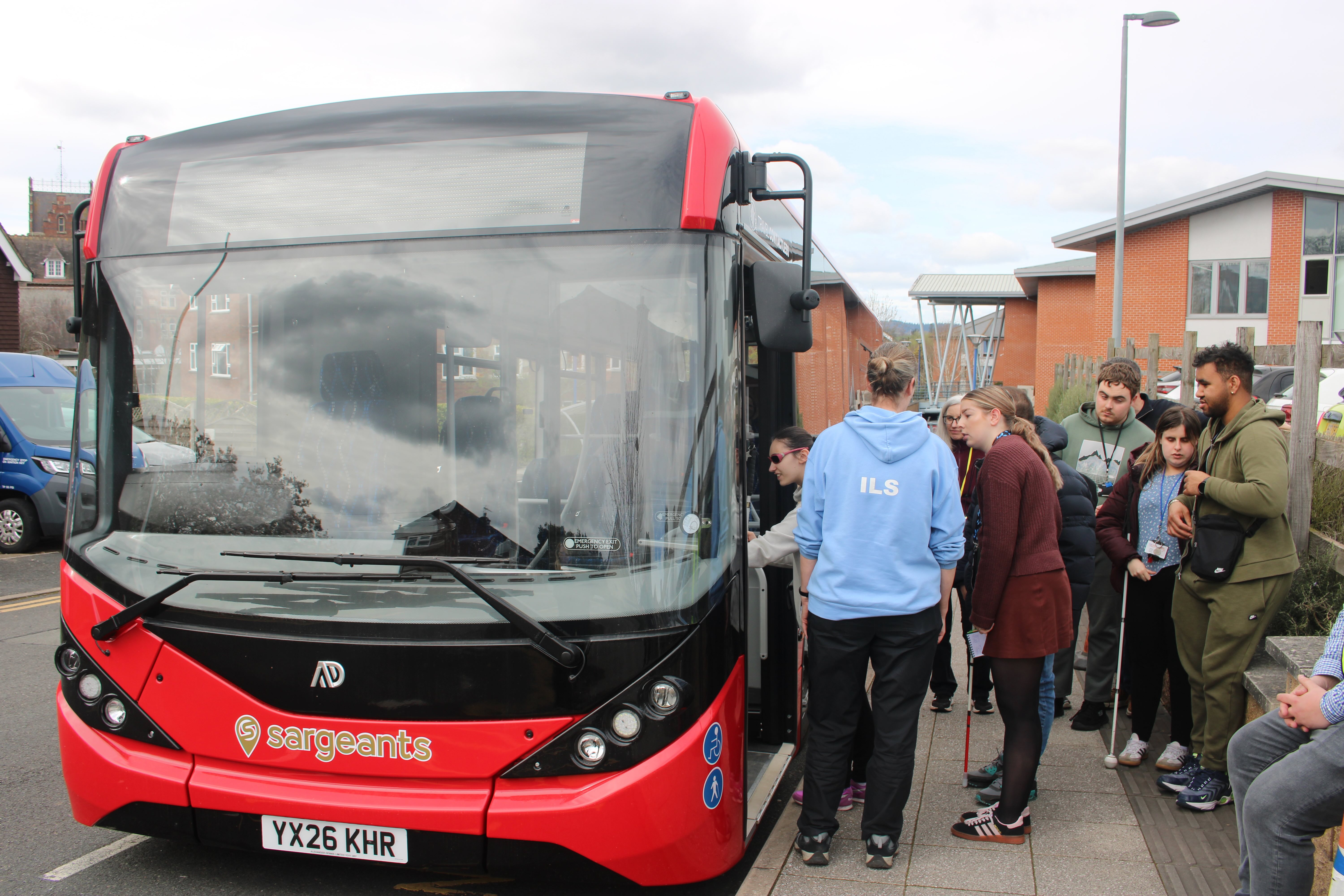 Students line up next to the big red bus excited to explore it