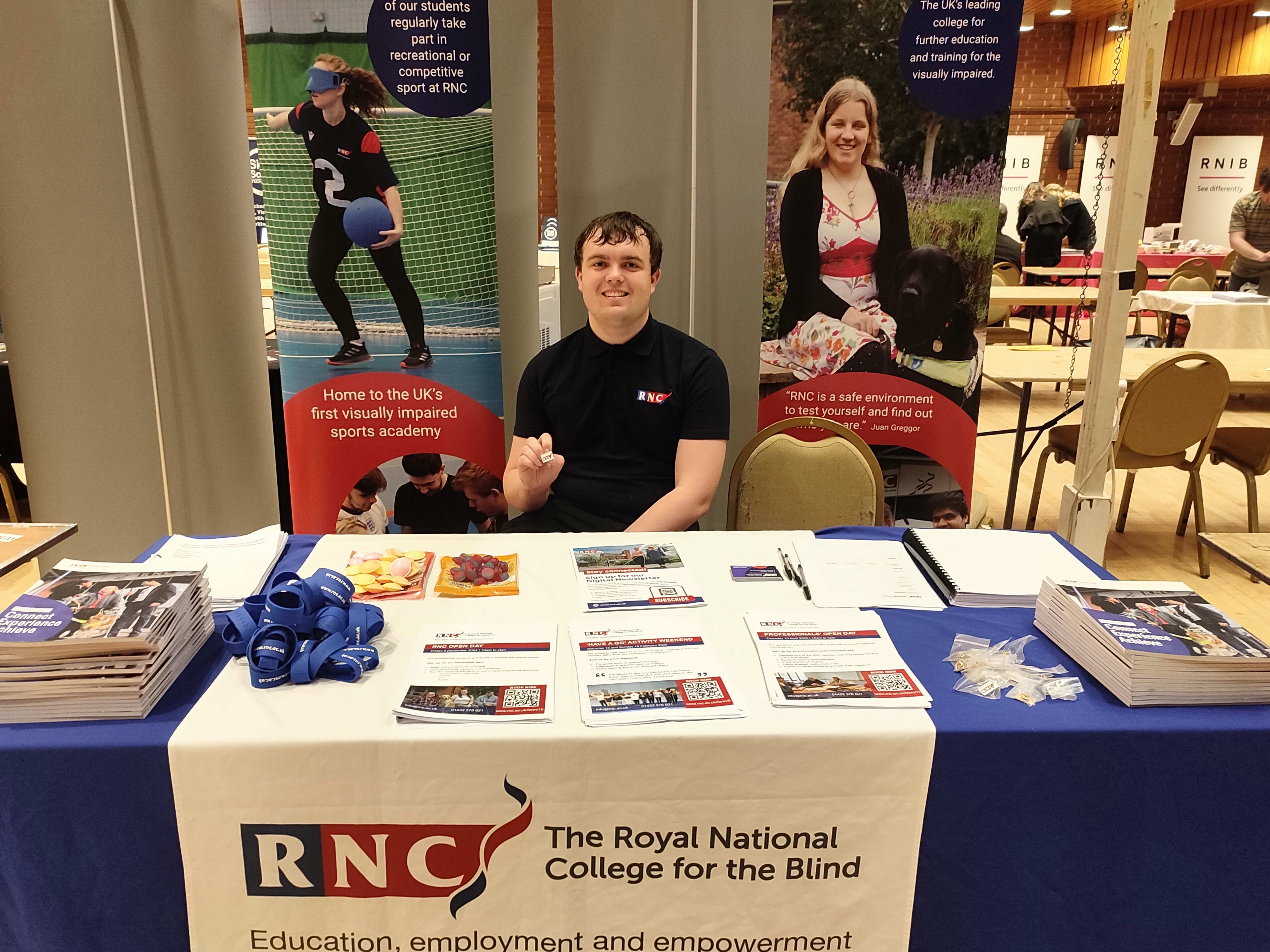 A male member of RNC staff sits behind a desk with RNC banners behind him