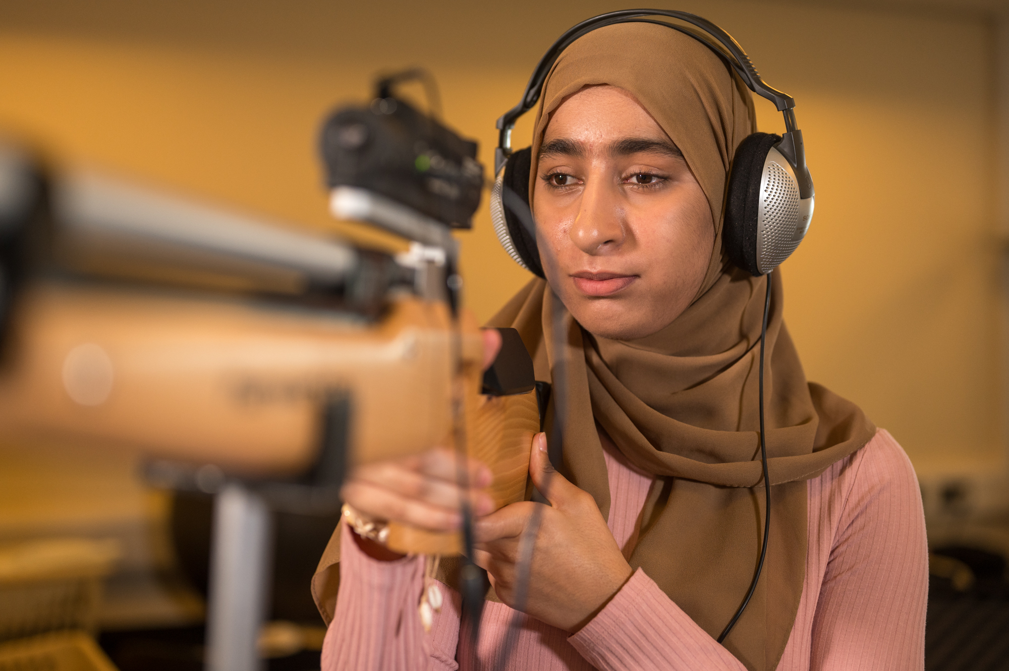 Humna wearing headphones, look ahead with both hands on the acoustic shooting rifle