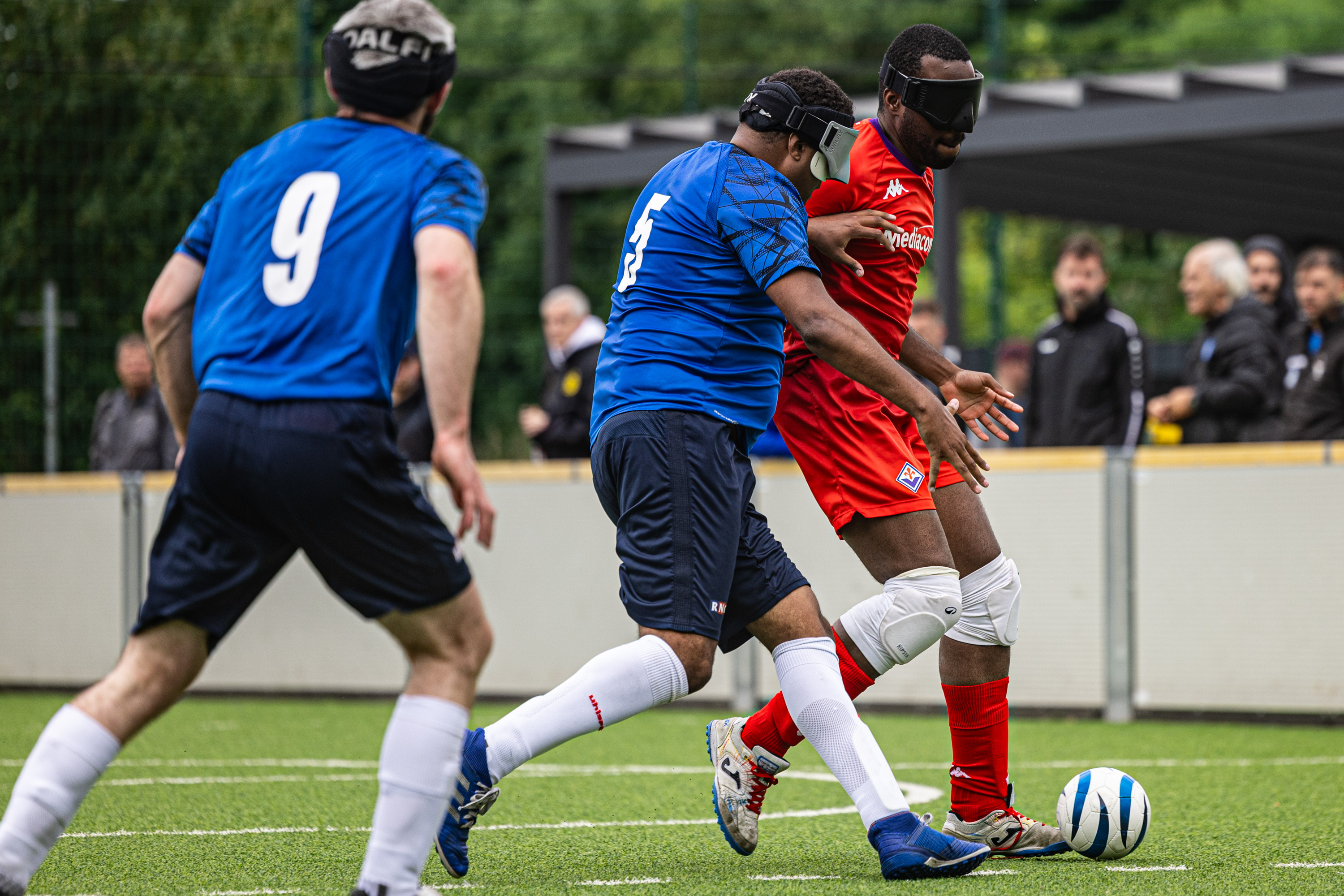 Mbuangi in a blue strip challenging Firenze's Iyobo in a red strip. Turnham for RNC is in the foreground 