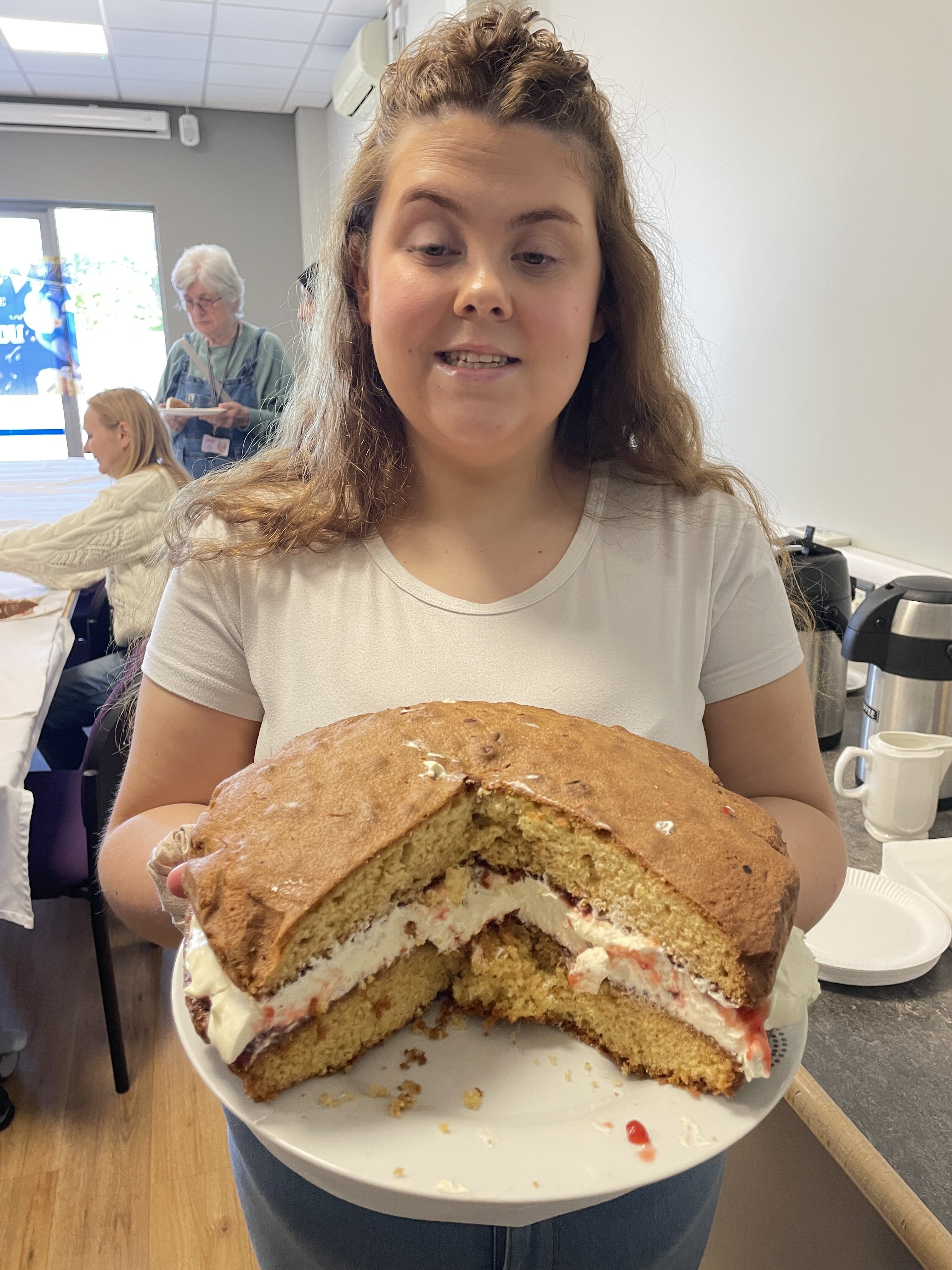 Reisha proudly holds up her Victoria Sponge which has had several slices taken out of it