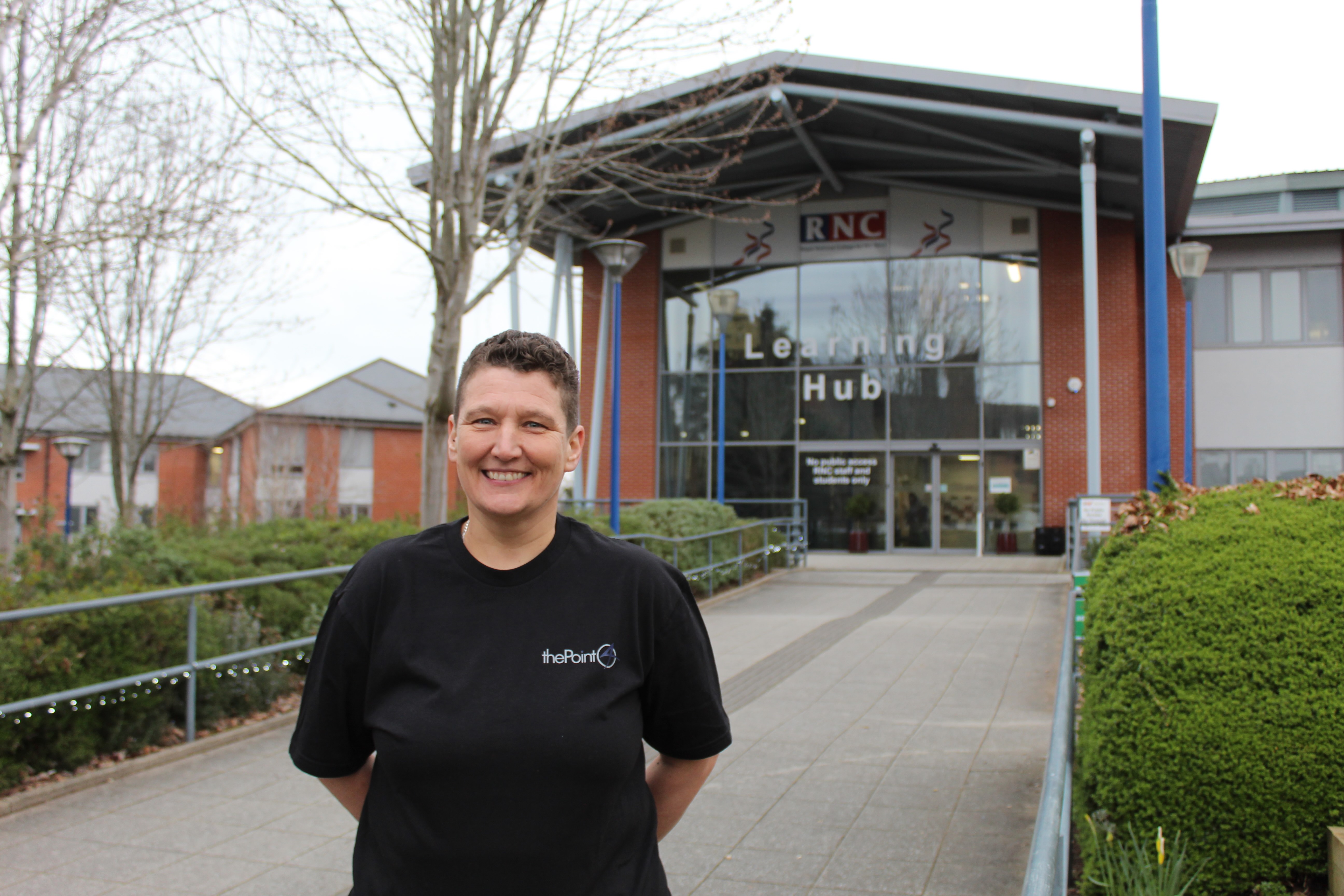 Tammy stands in front of the College entrance