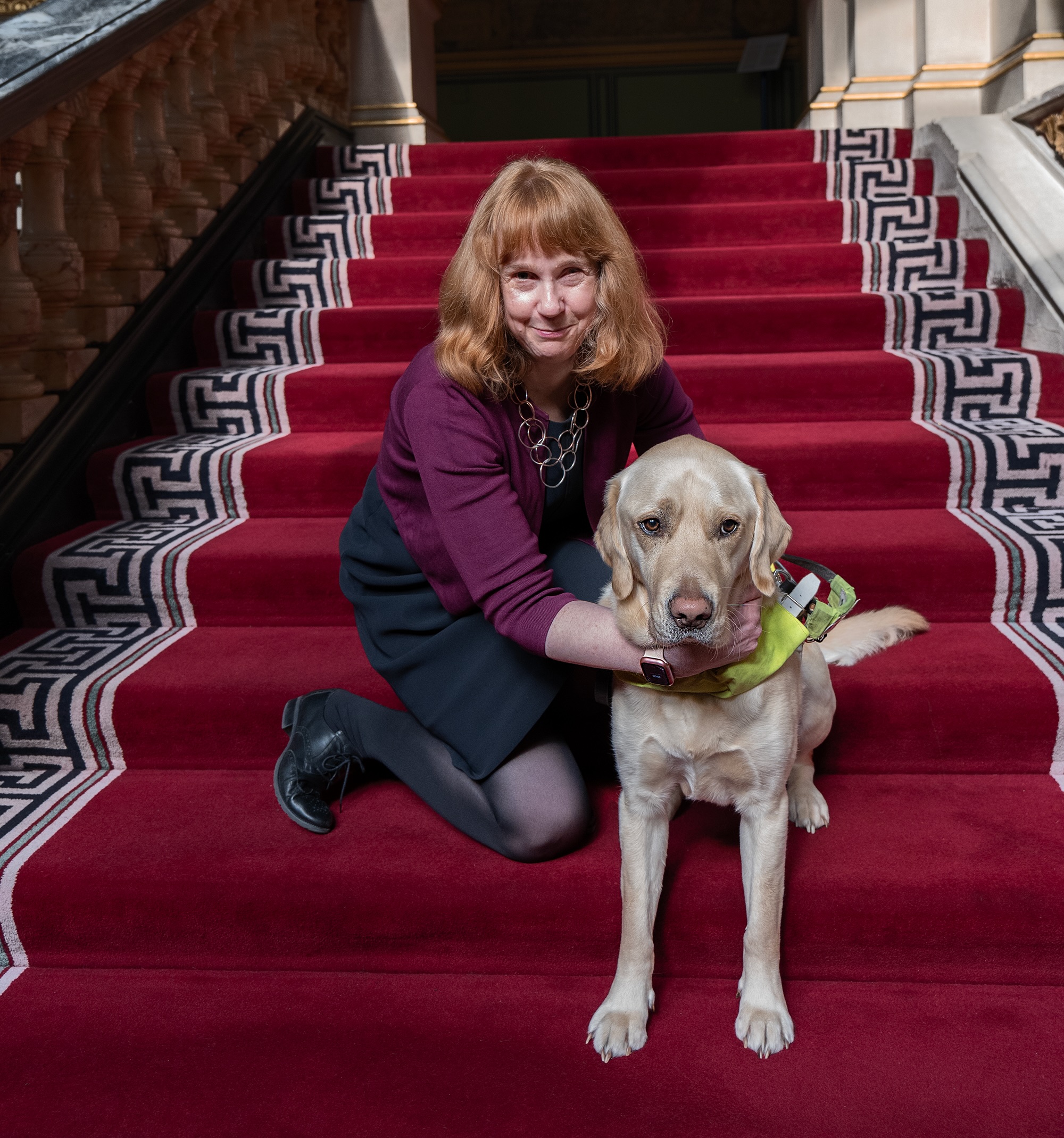 Victoria and Otto sitting on a grand red carpeted staircase
