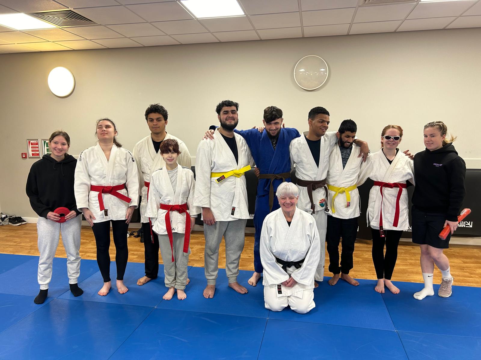 the full group of coaches and judokas showing off their newly acquired belts