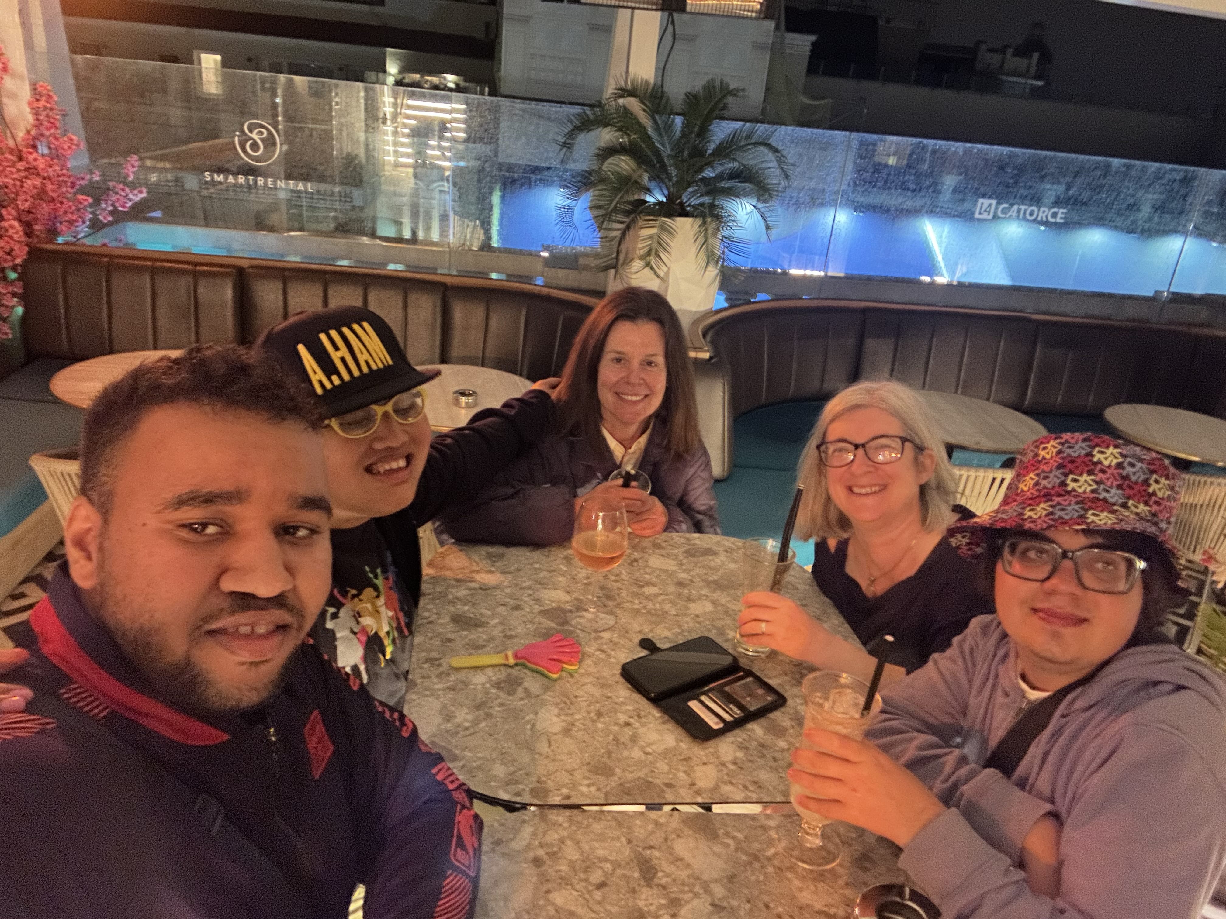 a small group sitting around a table with drinks. It's dusk and everyone is smiling